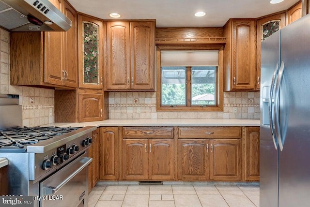 kitchen with stainless steel appliances, backsplash, light tile patterned flooring, and extractor fan