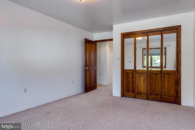 unfurnished bedroom featuring light colored carpet and a closet