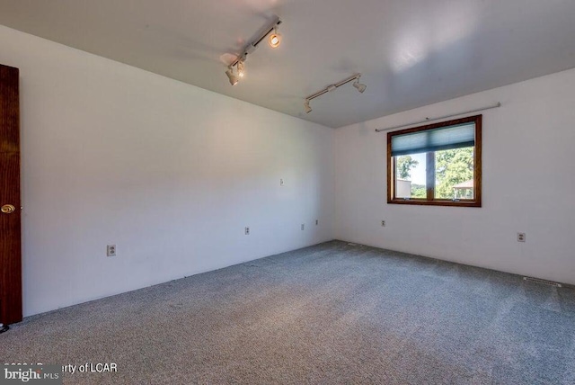 carpeted empty room featuring track lighting