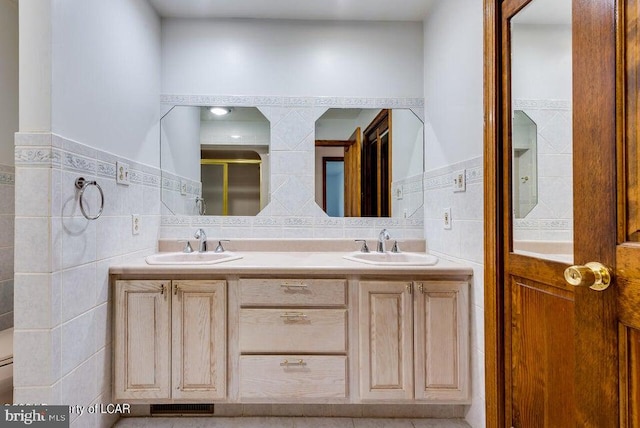 bathroom with vanity, tile walls, toilet, and a shower with door