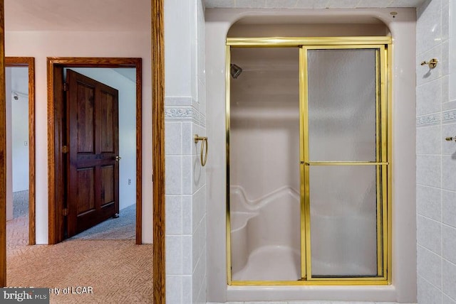 bathroom featuring tile walls and a shower with door