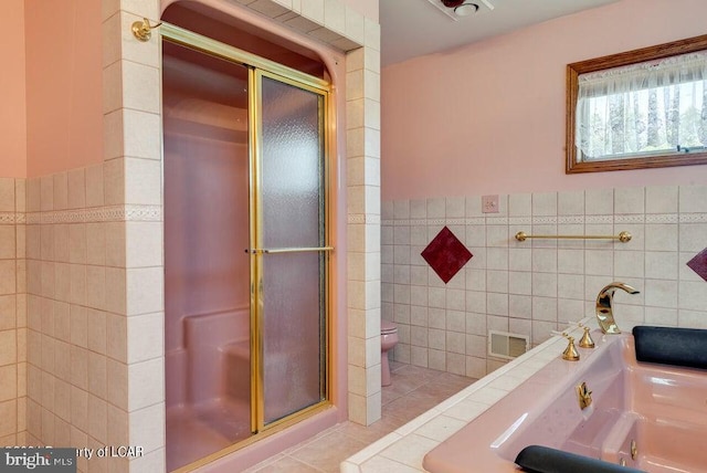 bathroom with tile walls, tile patterned flooring, toilet, and an enclosed shower