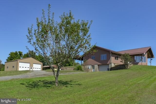 view of front of home featuring an outdoor structure, a front yard, and a garage