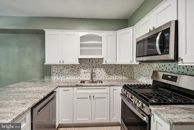 kitchen featuring light stone countertops, white cabinetry, sink, and stainless steel appliances