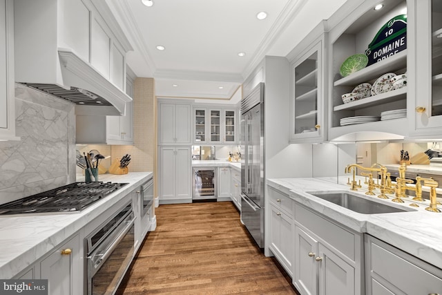 kitchen with sink, beverage cooler, light hardwood / wood-style flooring, built in appliances, and crown molding