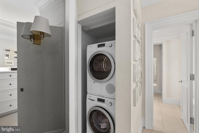 washroom featuring light tile patterned floors, ornamental molding, and stacked washing maching and dryer