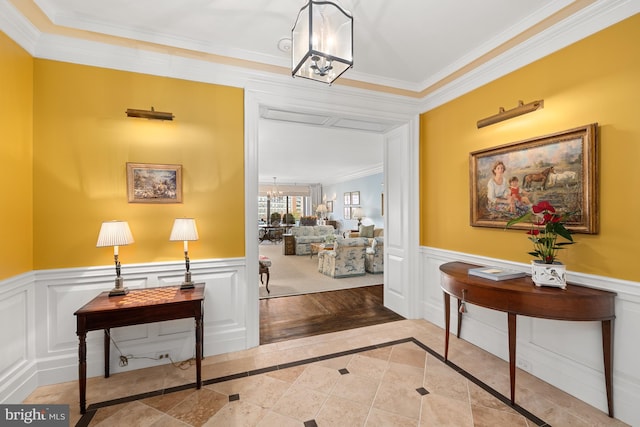 hall featuring light wood-type flooring, a chandelier, and ornamental molding