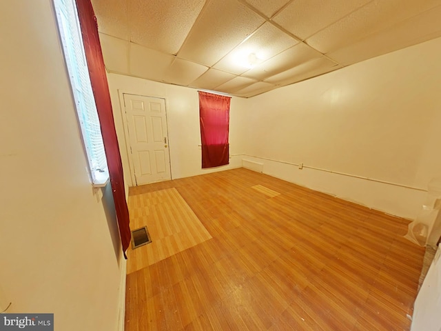 empty room featuring a drop ceiling and hardwood / wood-style flooring