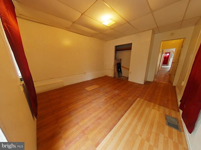 unfurnished room featuring a drop ceiling and hardwood / wood-style floors