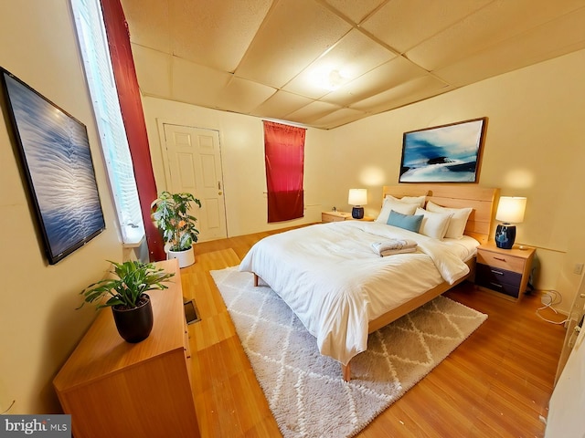 bedroom with a paneled ceiling and hardwood / wood-style floors