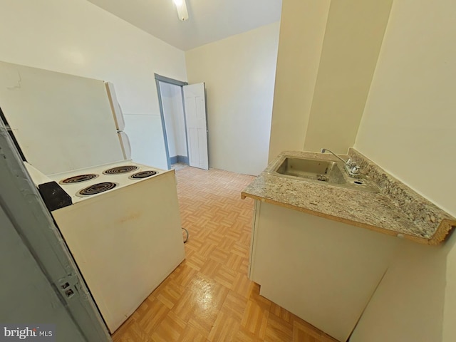 kitchen featuring light stone counters, light parquet floors, sink, and white electric range