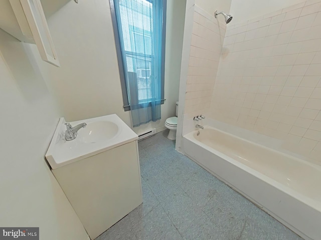 full bathroom with baseboard heating, tiled shower / bath, vanity, and toilet