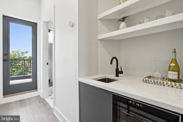 bar featuring sink, light hardwood / wood-style flooring, and wine cooler