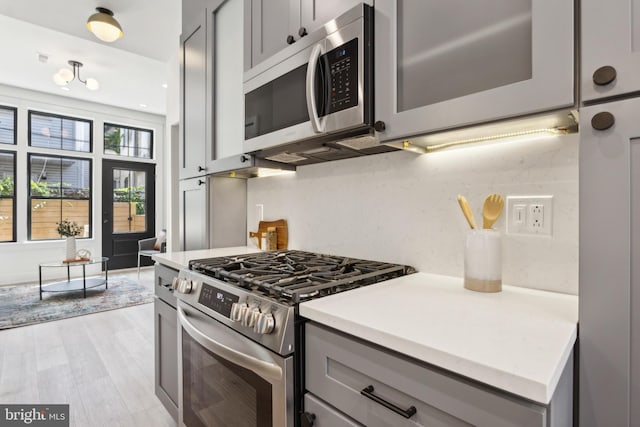 kitchen featuring gray cabinets, stainless steel appliances, tasteful backsplash, and light hardwood / wood-style flooring