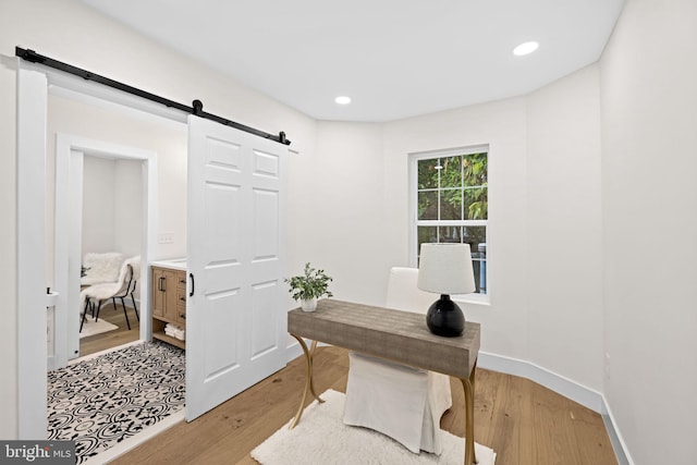 office with light wood-type flooring and a barn door