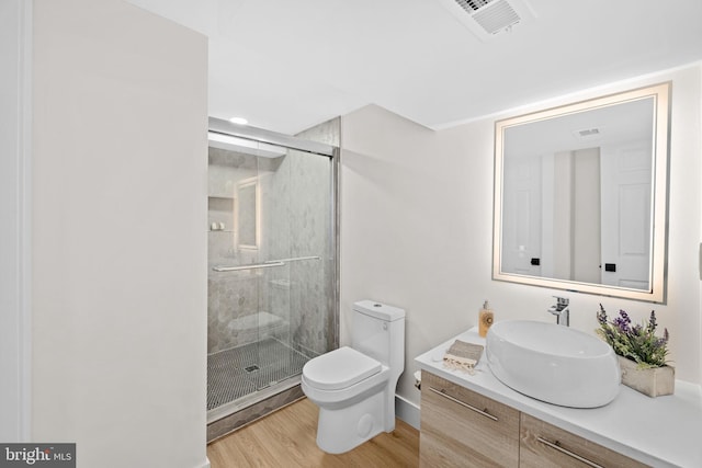 bathroom with hardwood / wood-style floors, walk in shower, vanity, and toilet