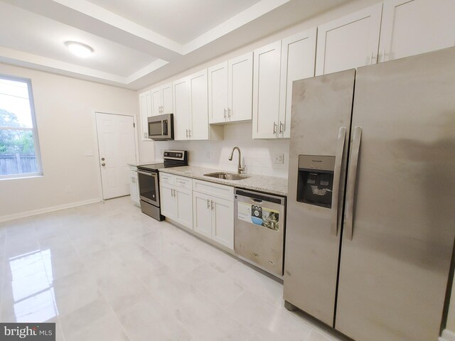 kitchen featuring appliances with stainless steel finishes, sink, light stone counters, and white cabinets