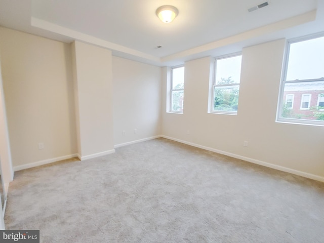 carpeted empty room featuring a tray ceiling