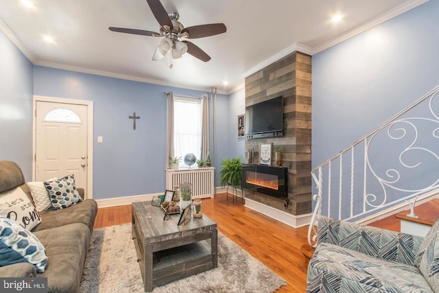 living room featuring hardwood / wood-style floors, a large fireplace, radiator heating unit, and ceiling fan