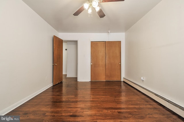 unfurnished bedroom with a baseboard heating unit, dark wood-type flooring, ceiling fan, and a closet