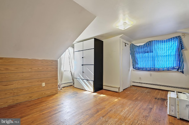 additional living space with light hardwood / wood-style floors, a baseboard radiator, and lofted ceiling