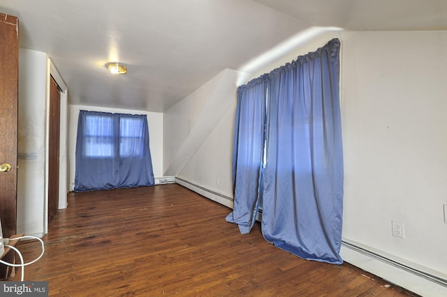 spare room featuring dark hardwood / wood-style flooring, lofted ceiling, and a baseboard heating unit