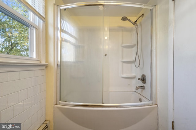 bathroom with tile walls and bath / shower combo with glass door