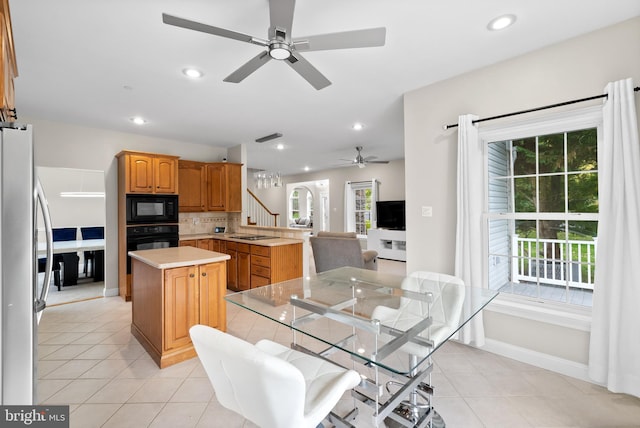 kitchen featuring decorative backsplash, kitchen peninsula, a kitchen island, black appliances, and ceiling fan