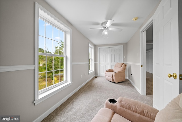 living area featuring a wealth of natural light, ceiling fan, and carpet flooring