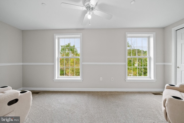 living area featuring ceiling fan, carpet flooring, and a wealth of natural light