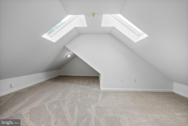 bonus room with vaulted ceiling with skylight and light colored carpet