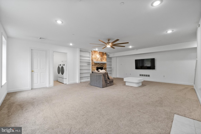 unfurnished living room with light colored carpet, a fireplace, separate washer and dryer, ceiling fan, and built in features