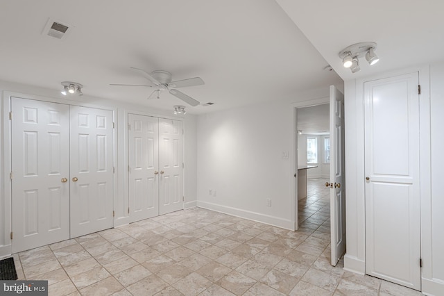 unfurnished bedroom featuring multiple closets and ceiling fan