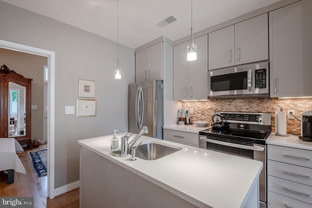 kitchen with a kitchen island, pendant lighting, stainless steel appliances, hardwood / wood-style floors, and sink