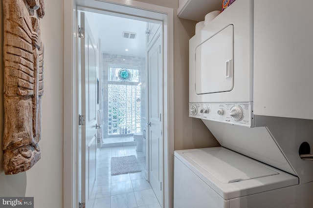 laundry room featuring light tile patterned floors and stacked washing maching and dryer