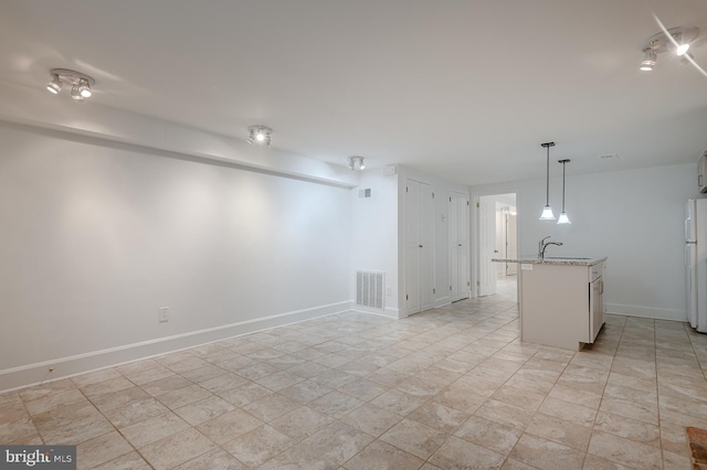 interior space featuring hanging light fixtures, light stone counters, and white refrigerator