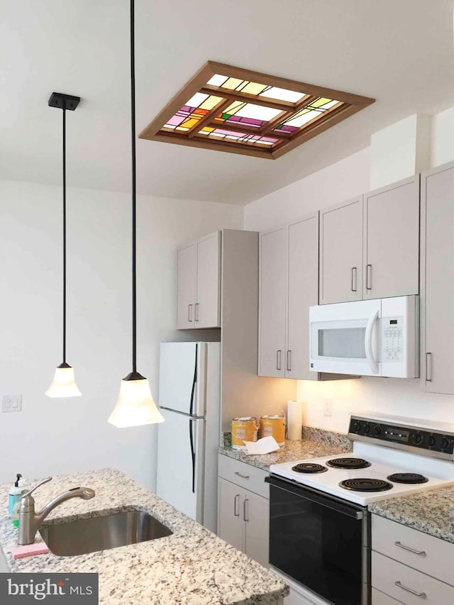 kitchen featuring a skylight, hanging light fixtures, sink, white appliances, and light stone countertops