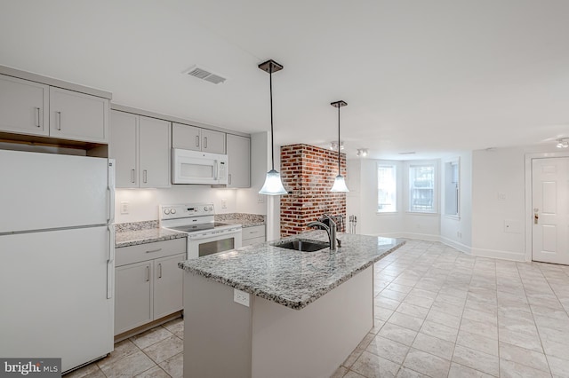 kitchen with white appliances, light stone countertops, decorative light fixtures, a kitchen island with sink, and sink