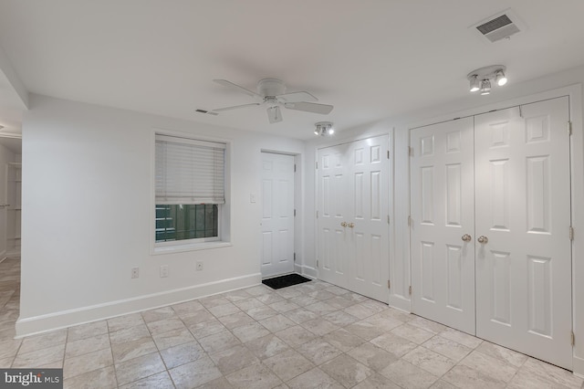 unfurnished bedroom with ceiling fan and multiple closets