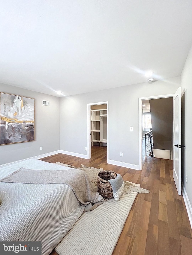 bedroom with a spacious closet, a closet, and hardwood / wood-style flooring