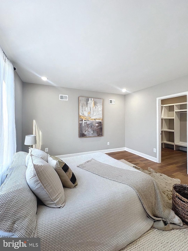 bedroom with wood-type flooring, a walk in closet, and a closet