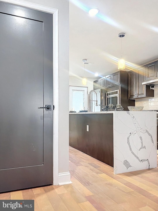 kitchen featuring pendant lighting, light hardwood / wood-style flooring, and tasteful backsplash