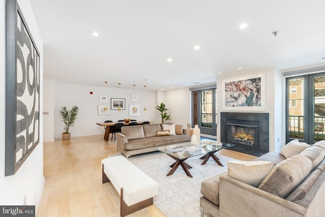 living area featuring light wood-style floors, a fireplace with flush hearth, a wealth of natural light, and recessed lighting