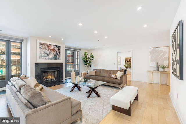 living room featuring a tile fireplace, light wood-style flooring, and recessed lighting