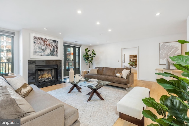 living area with a fireplace with flush hearth, recessed lighting, and light wood finished floors