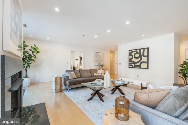 living area with light wood finished floors, a fireplace with flush hearth, visible vents, and recessed lighting