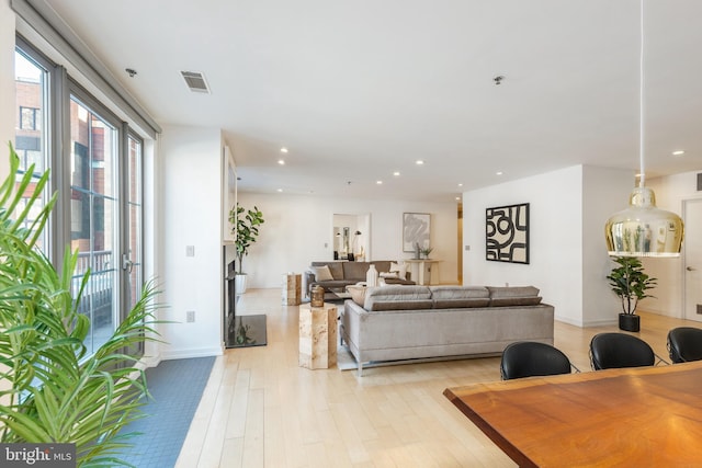 living room featuring recessed lighting, baseboards, visible vents, and light wood finished floors