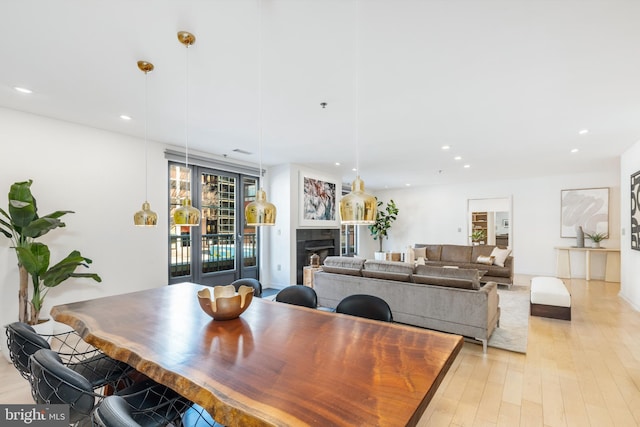 dining space with recessed lighting, a tile fireplace, and light wood-style floors