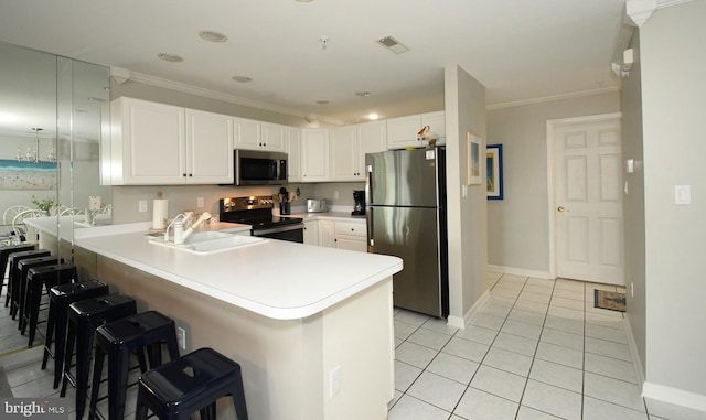 kitchen with appliances with stainless steel finishes, white cabinets, a breakfast bar, kitchen peninsula, and sink