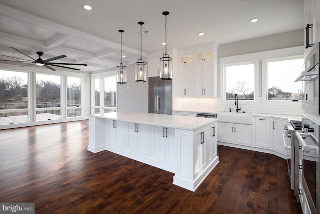 kitchen with dark wood-type flooring, tasteful backsplash, white cabinets, stainless steel appliances, and a center island